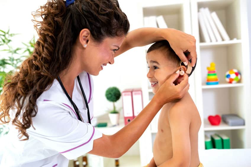 Placement of the hearing aid medical device Little boy getting his hearing aids