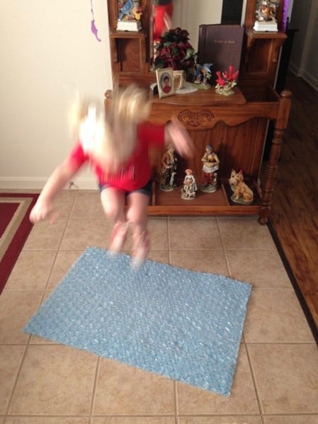 Jumping little girl jumping on bubble wrap to stimulate the eustachian tubes