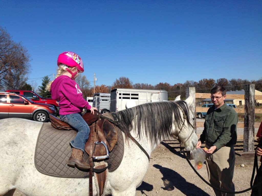 riding-a-horse Preschool girl on a horse watching uncle feed horse carrots.