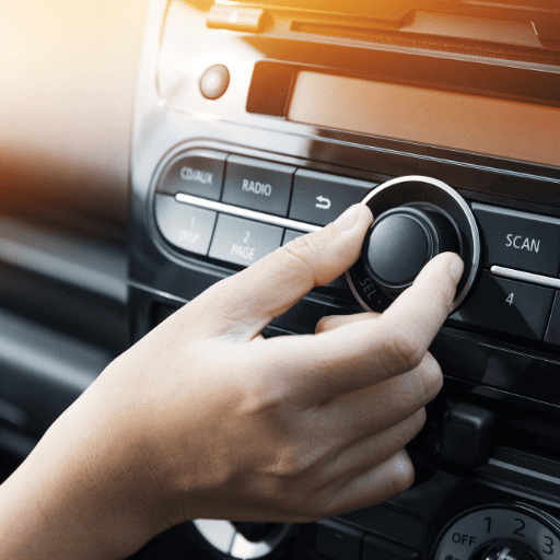 a hand turning down the volume in the car to demonstrate safe listening habits.