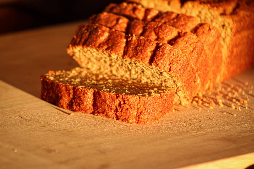 gluten free holiday pumpkin bread on a wooden cutting board with a few slices falling forward