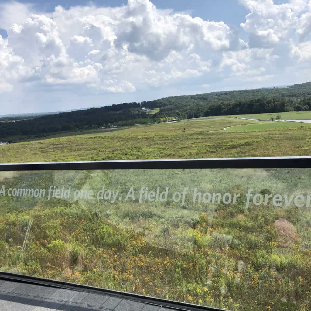 flight 93 September 11, memorial. view from the deck looking out over the grassy field with trees on the horizon. The glass railing has a quote written in white letters