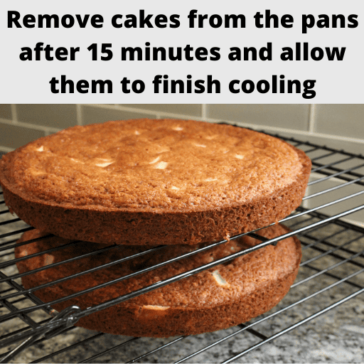 Two apple spice cake layers that have been removed from their pans sitting on stacked cooling racks. They are sitting on the counter.