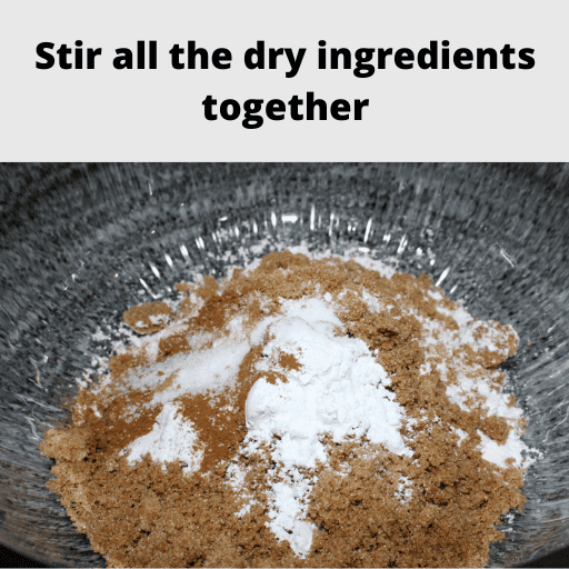 Large glass bowl filled with all the dry ingredients for apple spice cake.