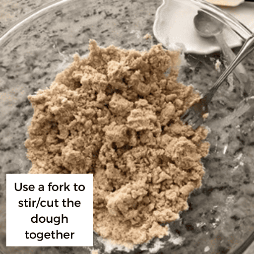 Gluten and dairy free pie crust mixture cut together into a crumbly mixture. It is in a glass bowl with a fork in the bowl. The bowl is sitting on the countertop.