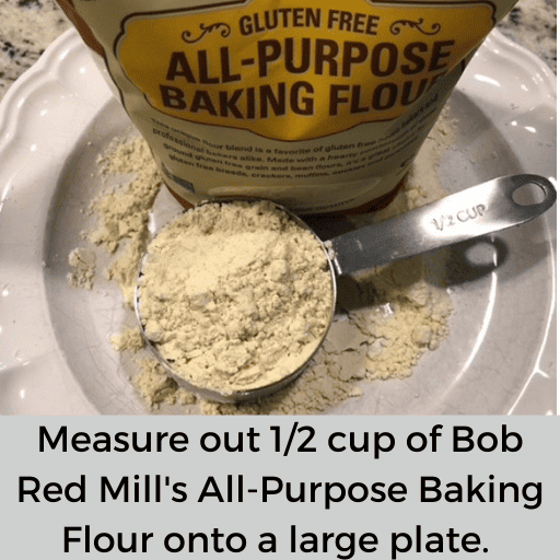 half cup of gluten free all-purpose baking flour sitting on a white plate. The flour bag is also sitting on the plate. There is flour on the plate around the bag and measuring cup.