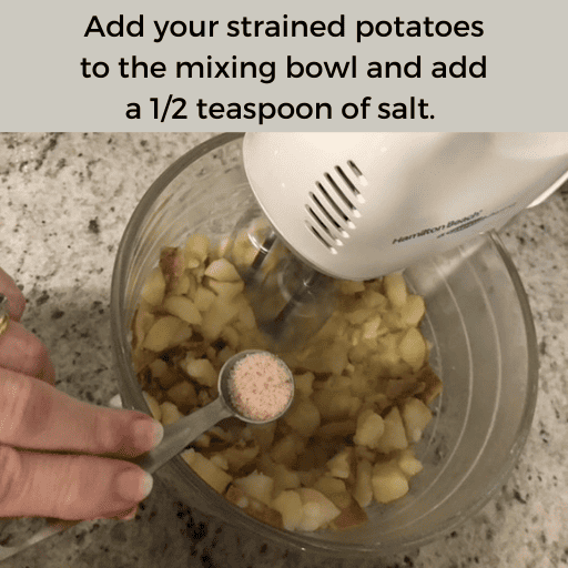 cooked diced potatoes in a glass mixing bowl on a white stand mixer. A hand is holding a half teaspoon of salt above the bowl. There is a gray box with black text at the top.