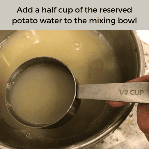 A 1/2 cup of reserved potato water being held above a metal bowl of potato water. There is a gray box with black text at the top.