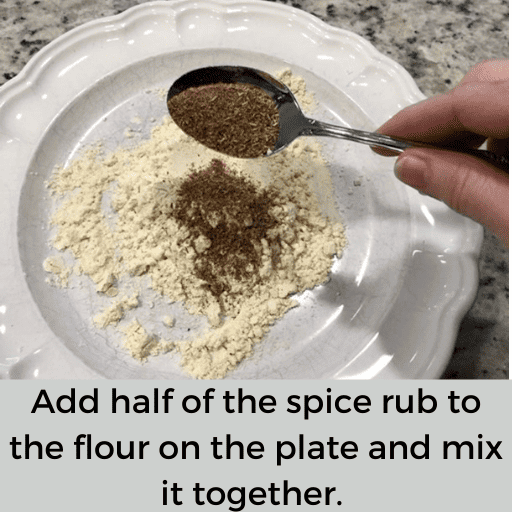 hand dumping a spoonful of the gluten free country fried steak spice rub into the flour on a white plate.