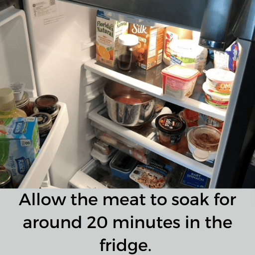 metal bowl of meat soaking sitting in the fridge. 