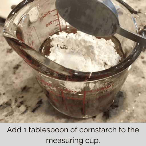 beef broth in a glass measuring cup with 1 tbsp of cornstarch