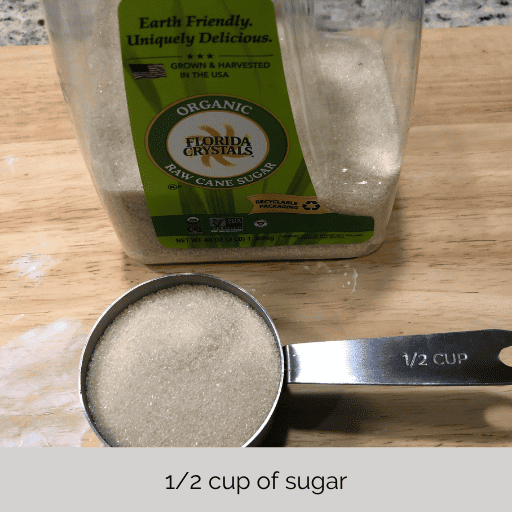 1/2 cup of sugar in a stainless steel measuring cup.