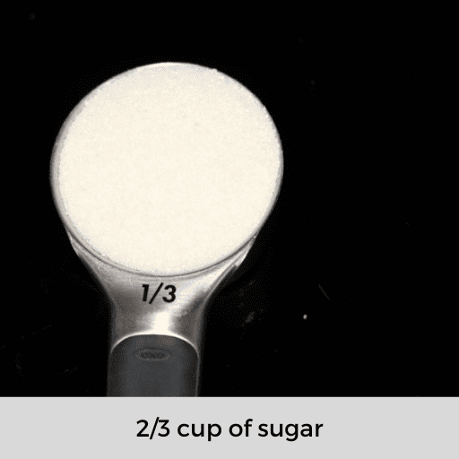 a 1/3 cup measuring cup with sugar on a black surface