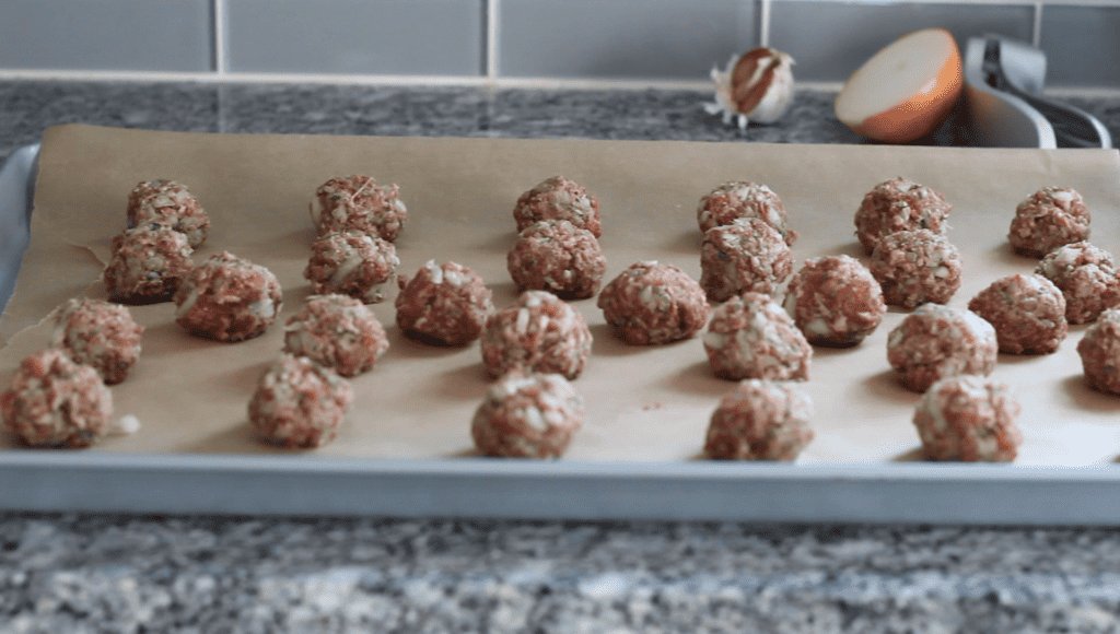 Raw gluten and dairy free meatballs rolled out on a baking sheet
