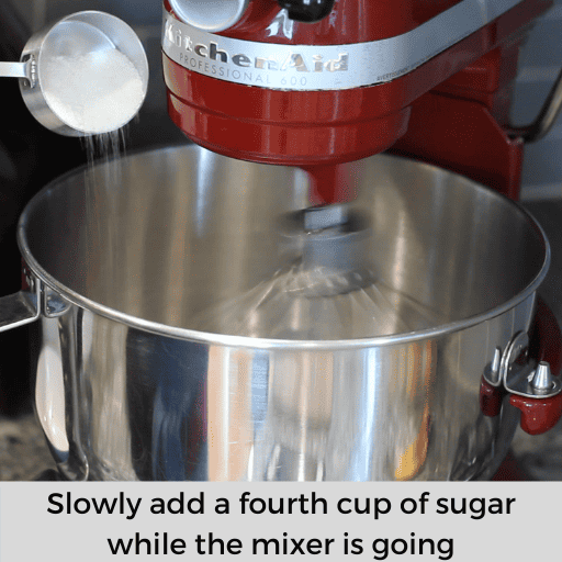 slowly adding a fourth cup of sugar to the mixing bowl of egg whites