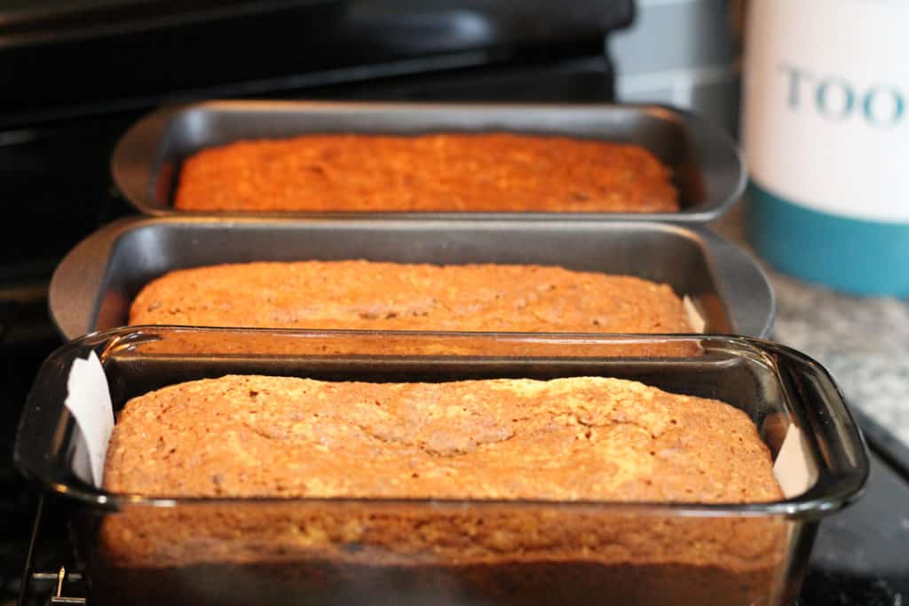 3 loaves of baked gluten and dairy free chocolate chip banana bread in loaf pans on the stovetop.