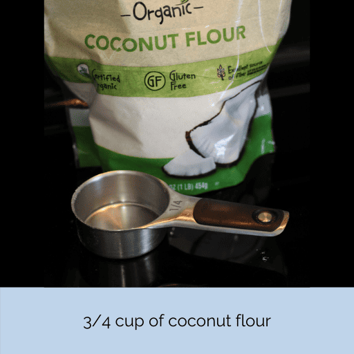A bag of coconut flour sitting on a black stovetop with a 1/4 measuring cup in front of it. 