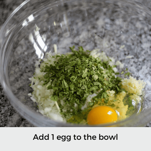 Glass bowl with chopped onion, seasonings, and one egg 