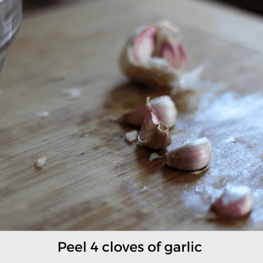 four garlic cloves on a cutting board