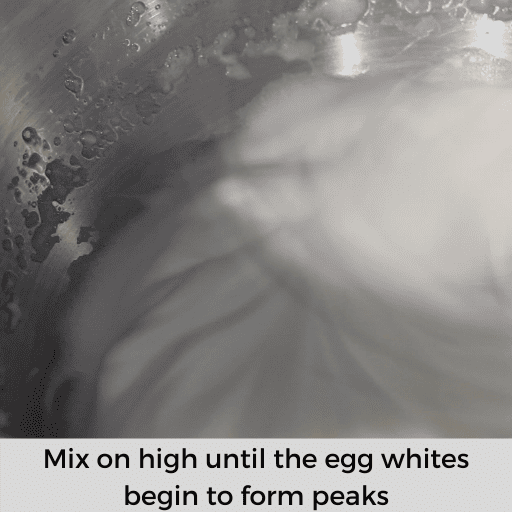 frothy egg whites in a metal mixing bowl