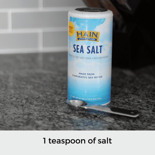 1 teaspoon sitting in front of a container of sea salt
