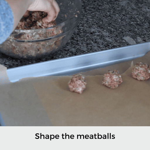 Shaping gluten and dairy free meatballs and placing them on a parchment lined baking sheet
