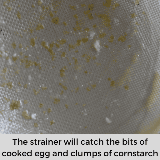 Fine mesh strainer with bits of cooked eggs and clumps of cornstarch. 