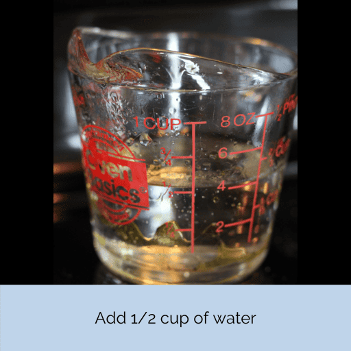 1/2 cup of water in a glass measuring cup sitting on a black stovetop.