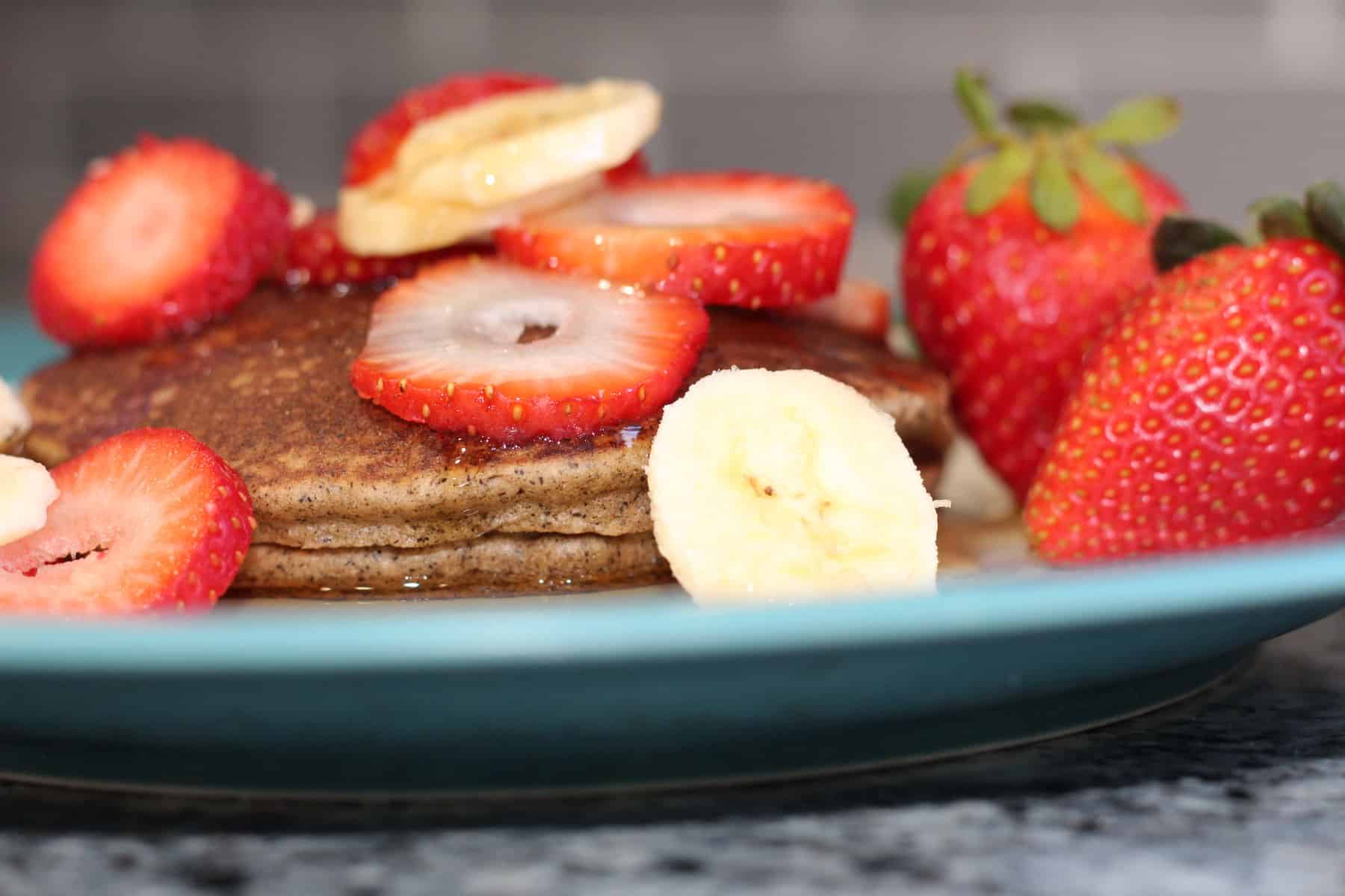 gluten and dairy free pancakes topped with sliced strawberries and bananas
