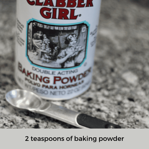 container of baking powder sitting behind a 1 teaspoon measuring spoon