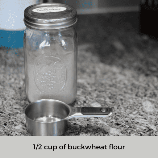 mason jar of buckwheat sitting behind a half cup measuring cup