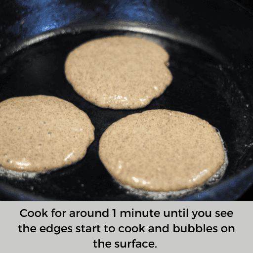 three gluten and dairy free pancakes cooking on a cast iron skillet