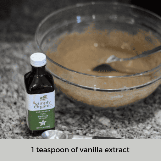 container of vanilla extract and a 1 teaspoon measuring spoon sitting on the counter in front of a bowl of gluten and dairy free pancake batter. 