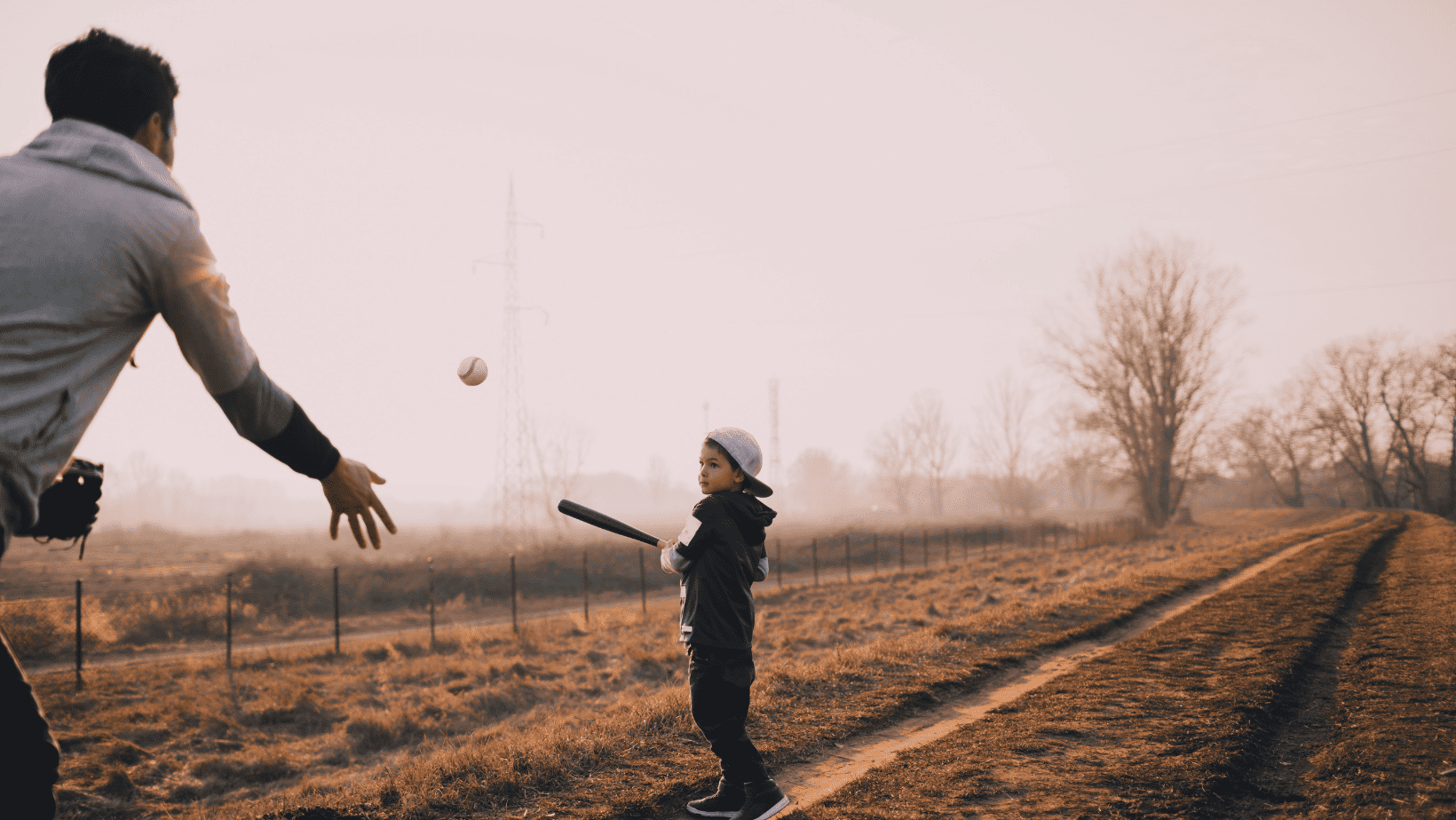 young boy playing baseball with his father outside