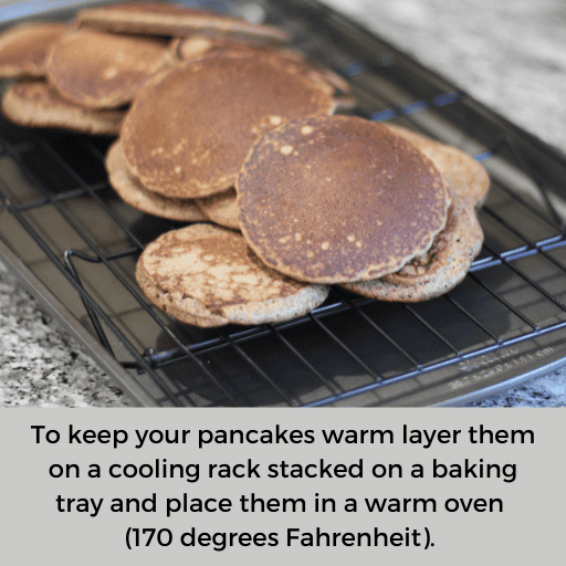 gluten and dairy free pancakes stacked on a cooling rack which is sitting in a cookie sheet