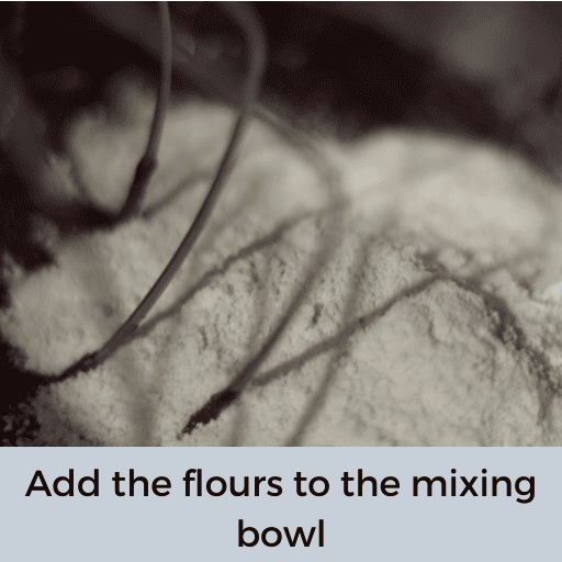 flour added to gluten and dairy free brownie batter in a mixing bowl with a whisk attachment