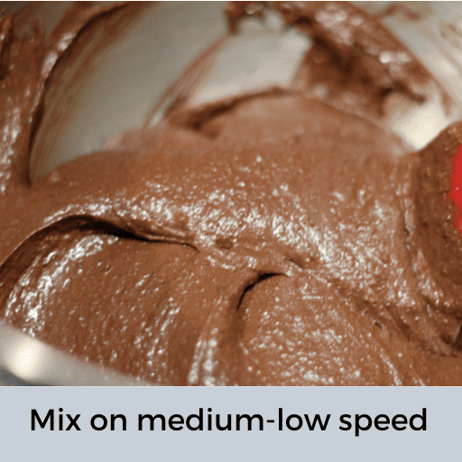 gluten and dairy free brownie batter all mixed up in a stainless steel mixing bowl with a red spatula