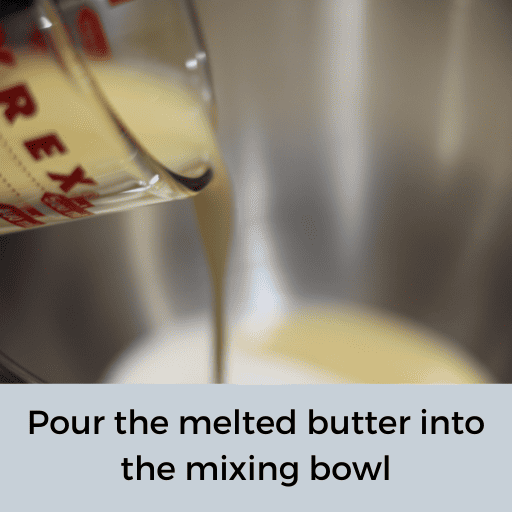 melted butter being poured from a glass measuring cup into a stainless-steel mixing bowl 