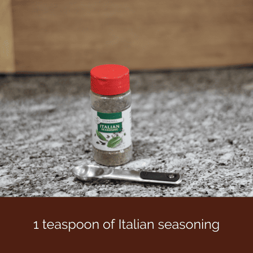 container of Italian seasoning with a teaspoon sitting in front of it. 