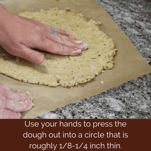 hand flattening out gluten and dairy free pizza crust dough into a circle. 
