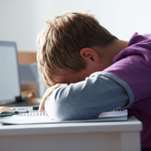 boy resting his head on his school books instead of using expressive speech