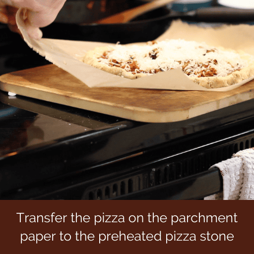 pizza on parchment paper being transferred to the preheated pizza stone. 