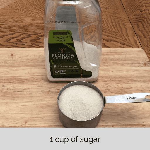 1 measuring cup of sugar with the container behind it.