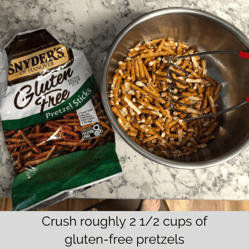 gluten free pretzels for strawberry pretzel salad in a metal mixing bowl with a potato masher