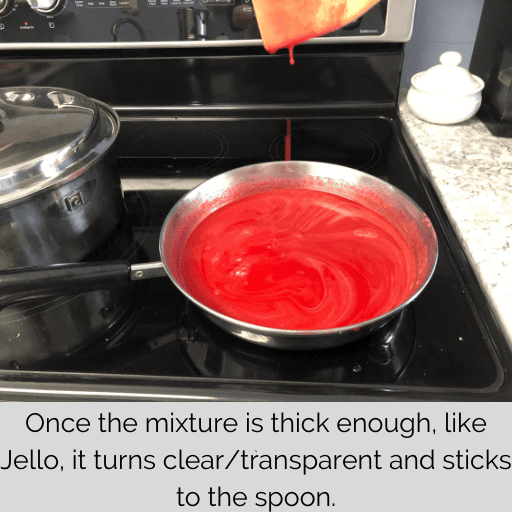 finished gel for the gluten and dairy free strawberry pie in the saucepan with the mixture dripping off of the spatula held above it. 