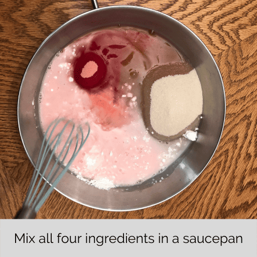 cornstarch, sugar, jello, and water added to a stainless steel saucepan with a blue rubber whisk