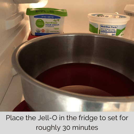 metal bowl with strawberry jell-o sitting in the fridge to set for the gluten and dairy free strawberry pretzel salad