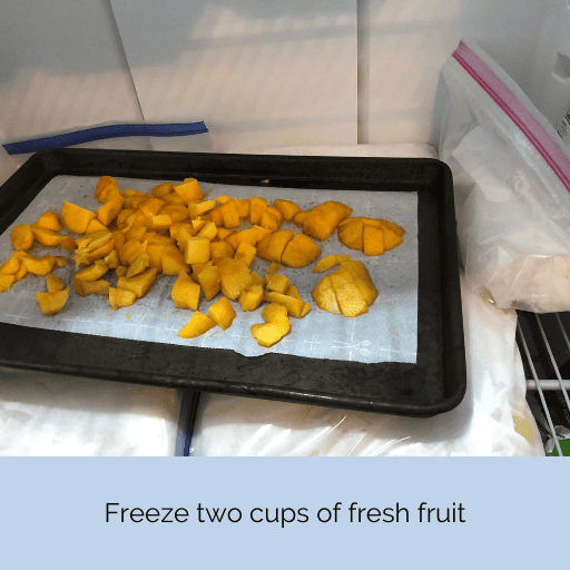 cookie sheet with parchment paper and diced peaches in the freezer