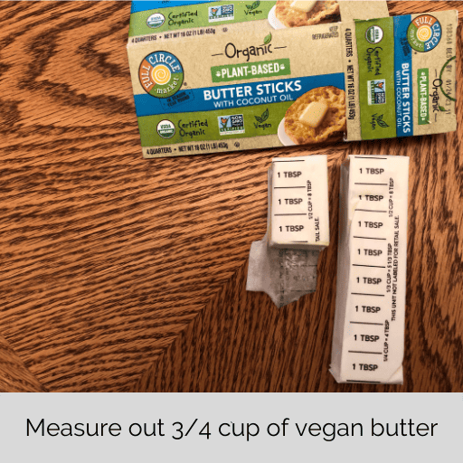 a stick and a quarter of vegan butter below the box on the wooden table