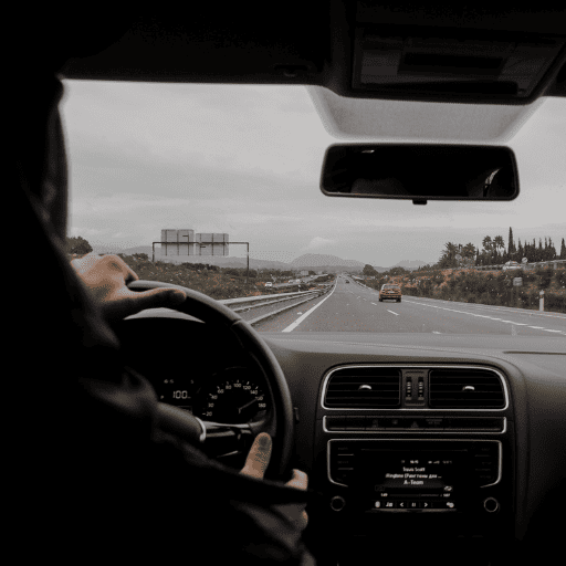 view from the backseat of a car of someone driving on the highway into the mountains on an overcast day with fog over the hills ahead